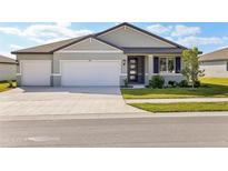 Two-car garage, light grey exterior, and a well-manicured lawn at 2012 Rosewood Dr, Bartow, FL 33830