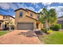 Two-story house with tan exterior, two-car garage, and palm trees at 1627 Lima Ave, Kissimmee, FL 34747