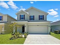 Two-story house with a beige exterior and a two-car garage at 7424 Bent Tree Loop, St Cloud, FL 34771