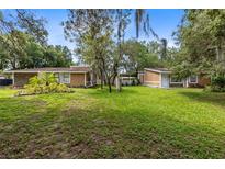 Two-story home with a large yard, lush landscaping, and a detached structure at 424 E Welch Rd, Apopka, FL 32712