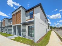 Modern two-story townhome with gray and wood siding, private patio, and walkway at 3229 Energy Dr, Kissimmee, FL 34747