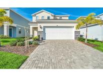 Two story home with a white garage door and a brick paved driveway at 1870 Summer Dr, Davenport, FL 33897