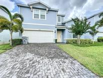 Two-story house with light blue siding, a white garage door, and a brick driveway at 2060 Lelani Cir, Davenport, FL 33897