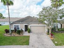 Tan one-story house with a two-car garage and landscaped yard at 4725 Cumbrian Lakes Dr, Kissimmee, FL 34746