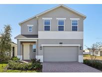 Two-story house with gray siding, two-car garage, and landscaping at 27512 Stellar Sea Way, Howey In The Hills, FL 34737