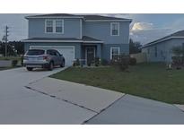 Two-story home with gray siding, attached garage, and landscaping at 181 Silver Maple Bnd, Davenport, FL 33837