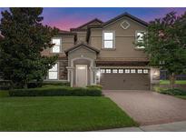 Two-story house with a tan exterior, brown garage door, and manicured lawn at 1424 Rolling Fairway Dr, Davenport, FL 33896