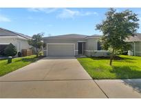 Newly constructed home with gray exterior, two-car garage, and landscaped lawn at 273 Summershore Dr, Auburndale, FL 33823