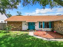 Brick home with teal front door, landscaped yard, and a large tree at 2720 Wekiva Meadows Ct, Apopka, FL 32712