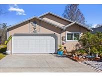 Tan house with a white garage door and landscaping at 132 Meadow Blvd, Sanford, FL 32771