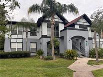 Two-story condo building with gray and white exterior, landscaping, and palm trees at 5525 Pga Blvd # 4614, Orlando, FL 32839