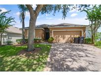 Tan one-story house with a two-car garage and well-manicured lawn at 619 Kensington Dr, Davenport, FL 33897