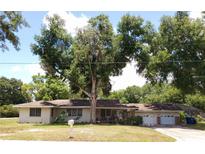 Ranch-style home with attached garage and mature landscaping at 1050 S Main Ave, Groveland, FL 34736