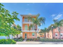 Two-story house with orange exterior, green accents, and palm trees at 8016 Flip Flop Way, Kissimmee, FL 34747