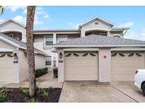 Tan two-story condo building with a double-car garage at 9429 Myrtle Creek Ln # 404, Orlando, FL 32832