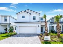 Two story home with white exterior, two car garage and landscaping at 7252 Oakmoss Loop, Davenport, FL 33837