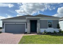 One-story home with gray exterior, brick paver driveway and landscaping at 6821 Serpent Hawk Lane St, Howey In The Hills, FL 34737