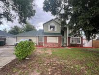 Two-story house with a green exterior, a red brick base, and a well-maintained lawn at 2603 Coventry Ln, Ocoee, FL 34761