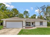 Single-story house with a white exterior, attached garage, and manicured lawn at 6292 Hemlock Rd, Ocala, FL 34472