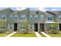 Modern townhome exterior with gray siding, stone accents, and landscaping at 1692 Tropical Palms Cir, Kissimmee, FL 34747
