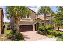 Two-story house with a brown garage door and palm trees at 8841 Rhodes St, Kissimmee, FL 34747
