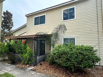 Tan two-story condo with covered patio, landscaping, and mature shrubs at 1123 Spring Meadow Dr # 1123, Kissimmee, FL 34741