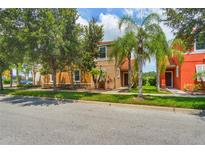 Two-story tan and orange house with palm trees and a grassy yard at 491 Las Fuentes Dr, Kissimmee, FL 34746