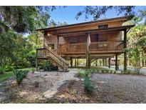 Rustic two-story home on stilts with a wooden exterior and large deck at 1205 Sutton Trl, Geneva, FL 32732