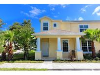 Two-story townhome with yellow exterior, white columns, and front porch at 17401 Serenidad Blvd, Clermont, FL 34714