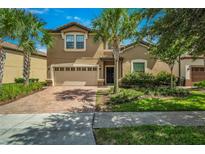 Two-story house with beige exterior, brick driveway, and palm trees at 8810 Macapa Dr, Kissimmee, FL 34747