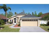 Tan one-story house with gray roof, two-car garage, and landscaped yard at 2635 Quarterdeck Ct, Kissimmee, FL 34743