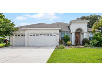 Two-car garage, light-colored stucco home with lush landscaping at 1712 Lime Dr, Winter Haven, FL 33881