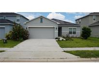House exterior with gray siding, two-car garage, and solar panels at 462 Hamlet Loop, Davenport, FL 33837
