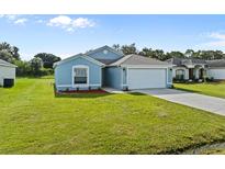Newly built light blue house with a two-car garage and well-maintained lawn at 656 Koala Ct, Kissimmee, FL 34759