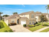 Two-story house with a tan exterior, a two-car garage, and well-maintained landscaping at 511 Pineloch Dr, Haines City, FL 33844