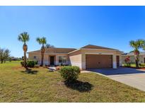 Tan house with brown garage doors, landscaping, and palm trees at 4054 Marina Isle Dr, Kissimmee, FL 34746