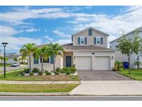 Two-story house with a two-car garage, landscaping, and palm trees at 1839 Good Neighbor Loop, Kissimmee, FL 34744