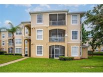 Three-story condominium building with balconies and lush landscaping at 8105 Coconut Palm Way # 203, Kissimmee, FL 34747