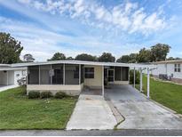 Single-wide manufactured home with carport and screened porch at 411 Palo Verde Dr, Leesburg, FL 34748