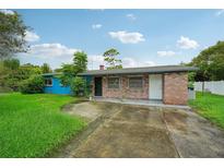 Brick home with blue painted siding, driveway, and grassy yard at 3034 Touraine Ave, Orlando, FL 32812