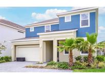 Two-story home with blue exterior, two-car garage, and palm trees at 4498 Monado Dr, Kissimmee, FL 34746