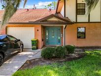 Inviting home exterior with teal front door and landscaping at 100 E Oak Terrace Dr # G1, Leesburg, FL 34748
