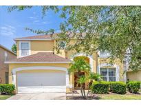 Two-story house with a yellow facade, white garage door, and manicured landscaping at 195 Hideaway Beach Ln, Kissimmee, FL 34746