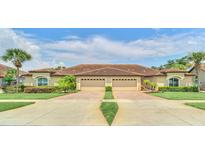 Tan two-story home with double garage and manicured lawn at 26841 Bella Vista Dr, Howey In The Hills, FL 34737