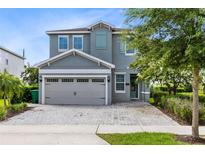 Two-story house with gray siding, shutters, and a paver driveway at 7443 Marker Ave, Kissimmee, FL 34747