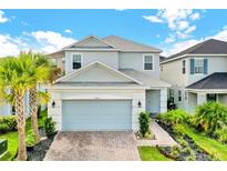 Two-story house with light gray siding, gray garage door, and landscaped yard at 2723 Plume Rd, Clermont, FL 34711