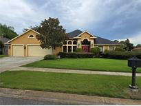Two-story house with yellow exterior, three-car garage and lush landscaping at 531 Soft Shadow Ln, Debary, FL 32713