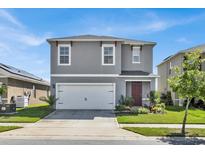 Two-story home with gray siding, two-car garage, and manicured lawn at 117 Eagleview Loop, Davenport, FL 33837