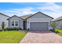 Two-story house with gray siding, two-car garage, and brick driveway at 3120 Legends Preserve Dr, Daytona Beach, FL 32124