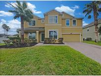 Two-story house with a yellow facade, palm trees, and a brick driveway at 15106 Ovation Dr, Winter Garden, FL 34787